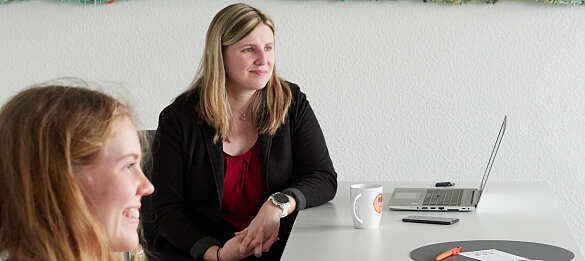 Carina Jahn sitzt am Tisch. Im Vordergrund ist Johanna Leewe, die das Interview geführt hat, zu sehen.