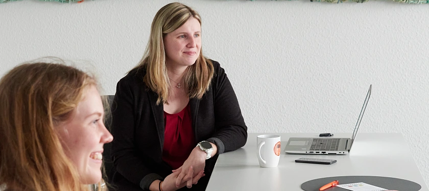 Carina Jahn sitzt am Tisch. Im Vordergrund ist Johanna Leewe, die das Interview geführt hat, zu sehen.