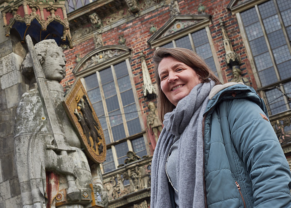 Nadja Niestädt steht lächelnd neben dem Bremer Roland.