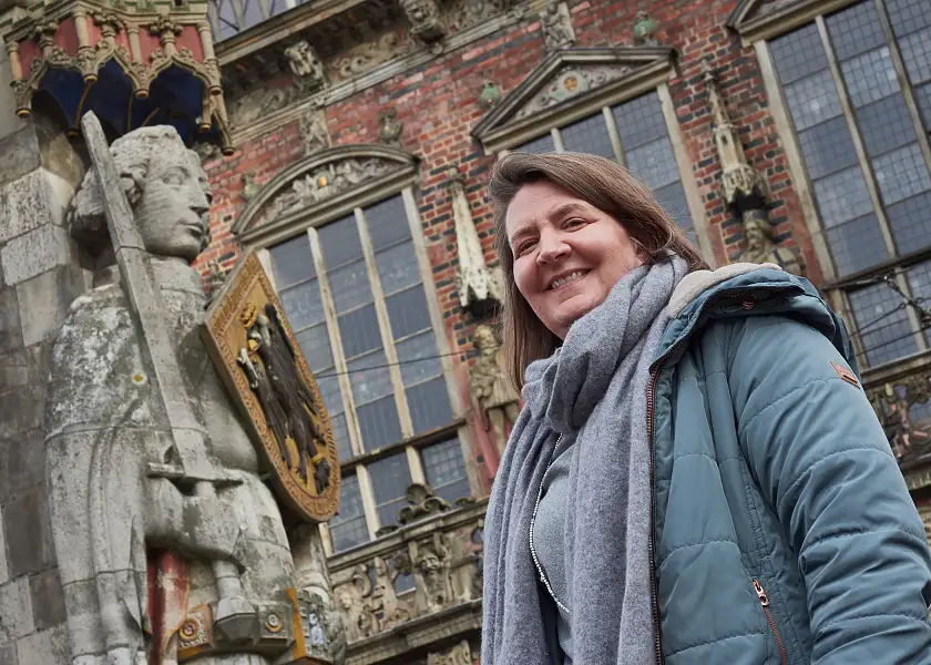 Nadja Niestädt steht lächelnd neben dem Bremer Roland.