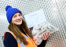 Frau mit blauer Pudelmütze und einer Plastiktüte voller tiefgekühlter Garnelen