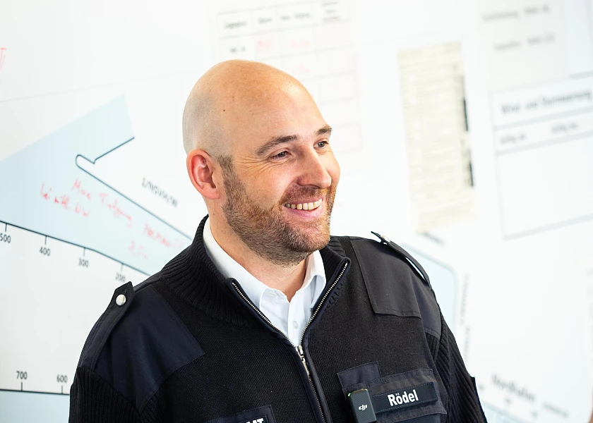 Nils Rödel steht vor der Hafenlandkarte und lächelt, der blick geht zur Seite weg