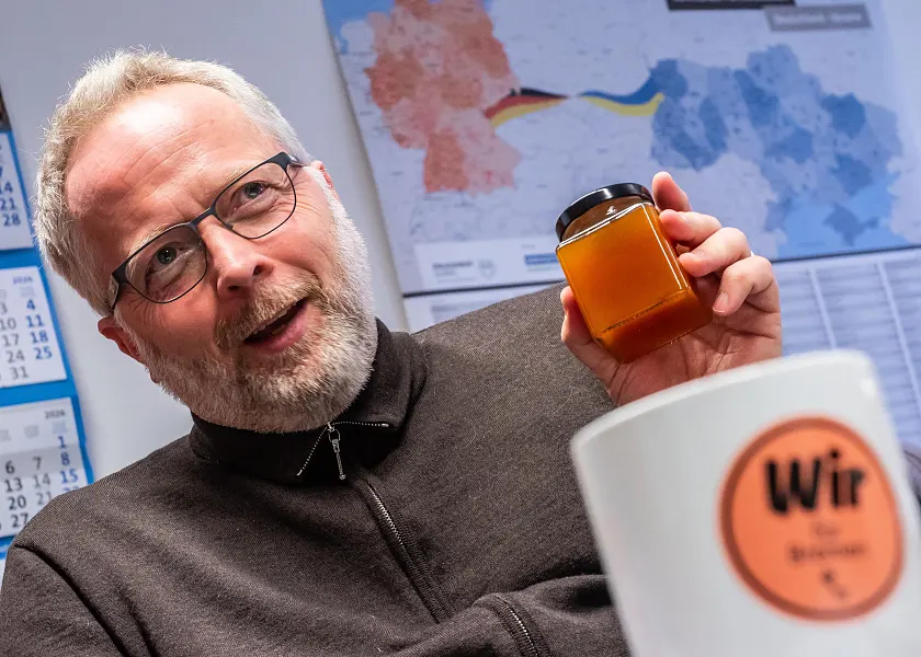 Andreas Weippert, mit kurzen grauen Haaren, hält ein Glas Marmelade in die Luft