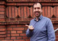 Foto von Simon Walz mit einem Holz-Bauklotz in der Hand.