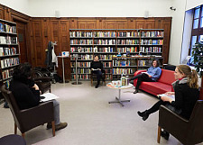Kriminalbibliothek innerhalb der Stadtbibliothek Bremens. Vier Personen sitzen für ein Gespräch um einen Tisch herum mit weitem Abstand.