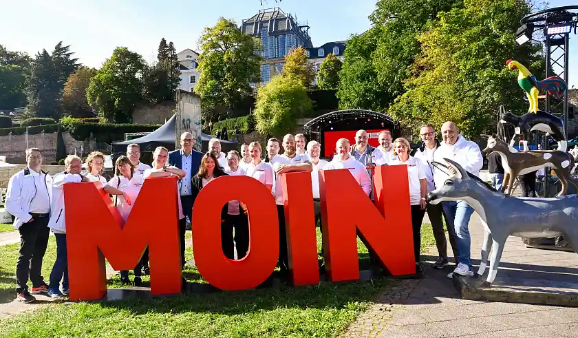 Team Bremen vor einer Bühne mit einem großen Moin-Schild beim Tag der Deutschen Einheit in Saarbrücken 2025