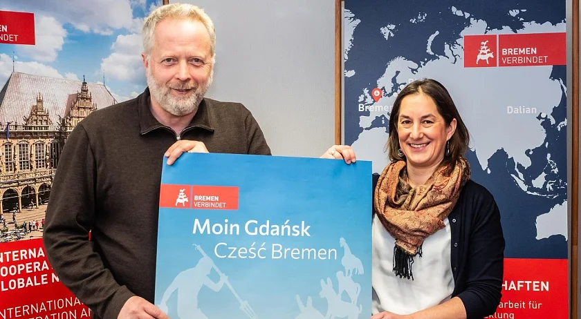 Randy Haubner (rechts) und Andreas Weippert (links) halten ein Plakat mit der deutsch-polnischen Aufschrift Moin Gdansk, Czesc Bremen hoch.