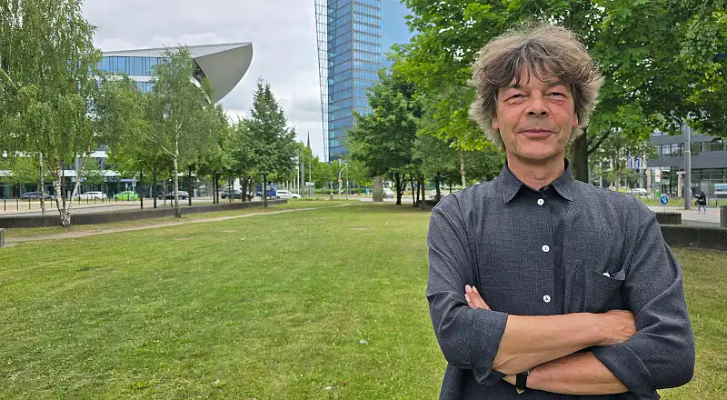 Stefan Wittig mit verschränkten Armen auf einer Wiese in der Bremer Überseestadt in der Nähe des Standorts der Senatorin für Umwelt, Klima und Wissenschaft