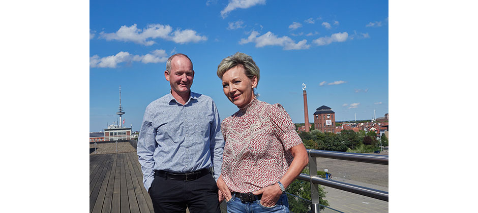 Kerstin Brockmüller und Jörg Meyer stehen vor blauem Himmel auf einer Dachterasse.
