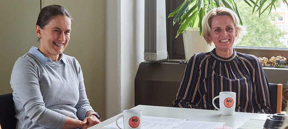 Die beiden Kolleginnen des Bereichs sitzen am Tisch und schauen freundlich auf ihre Interviewpartnerin der Leitstelle Arbeitgeberattraktivität